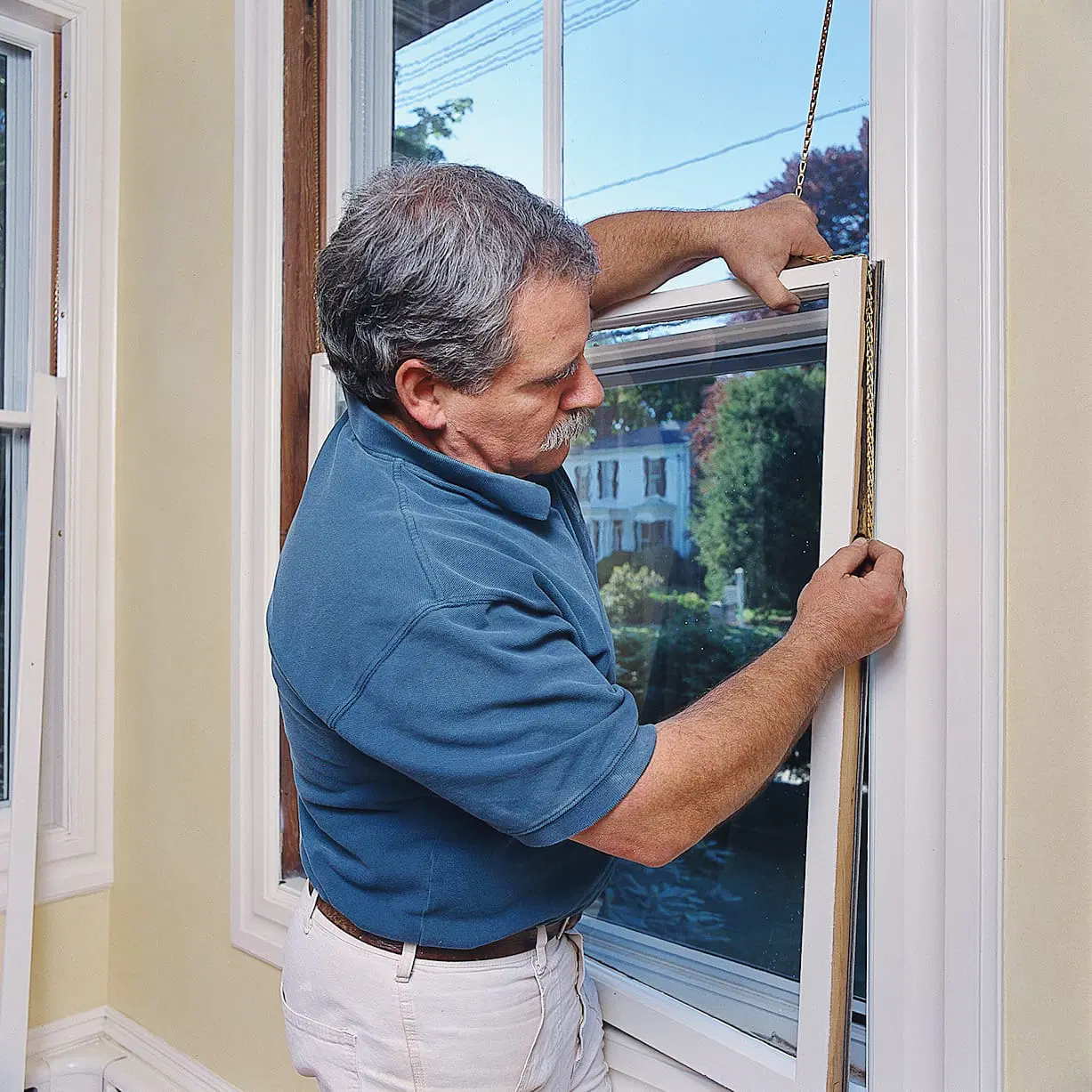 A man installing window sashes onto a window.