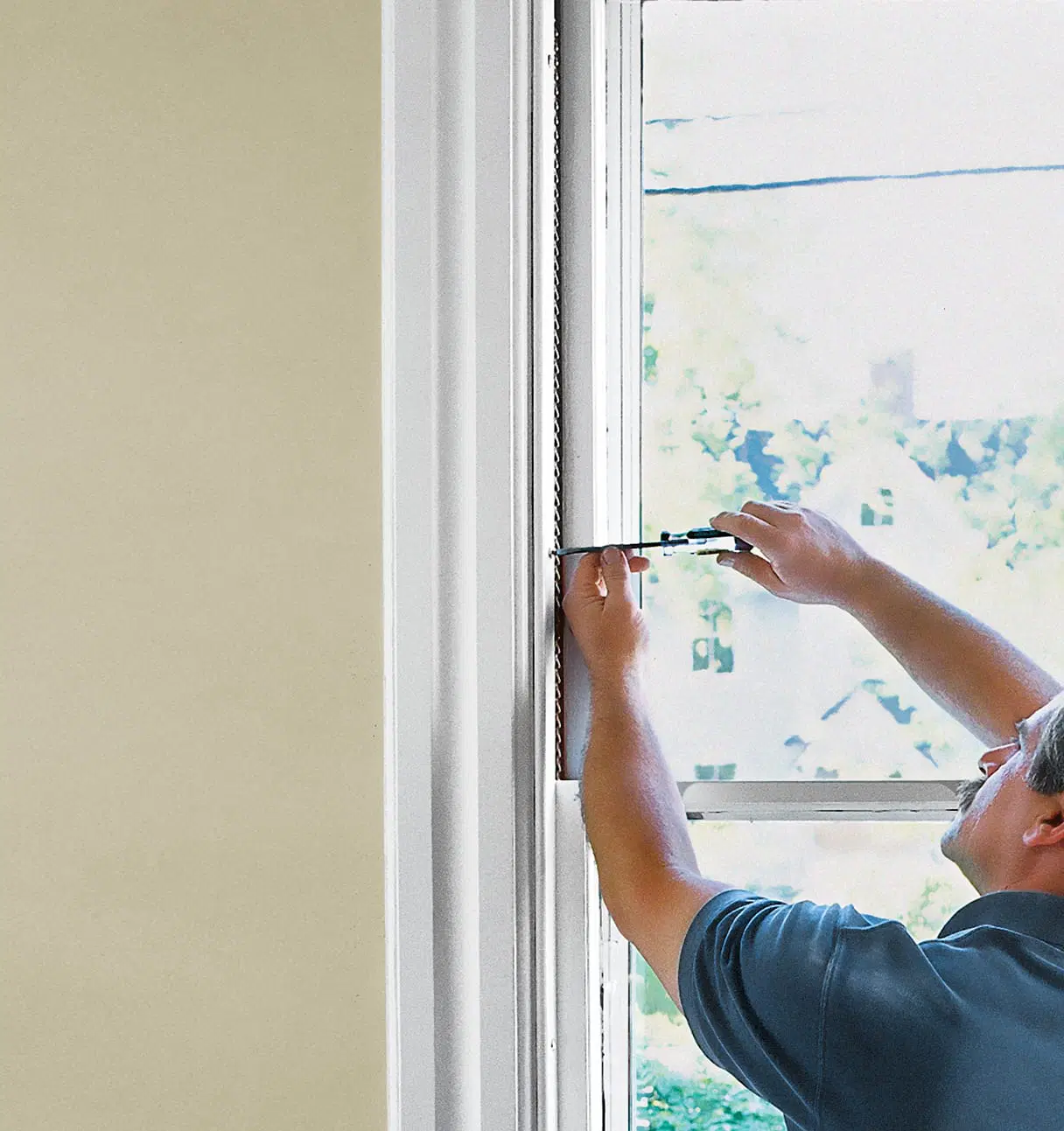 A man using a screwdriver to remove sashes from a window.