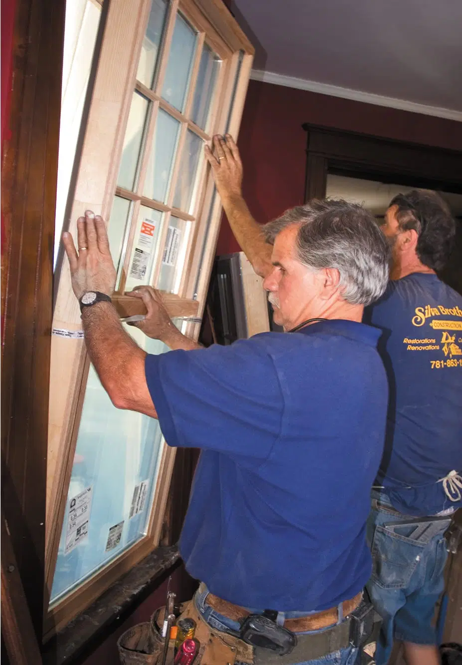 Tom Silva and another man install the replacement window.