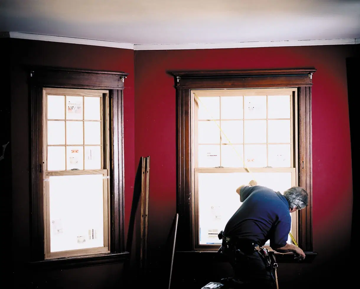 A man measures for replacement windows.