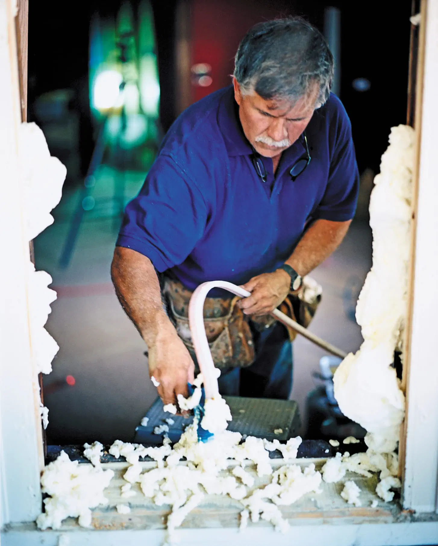 Tom Silva shoots expanding foam into a window frame to prepare it for the replacement window.