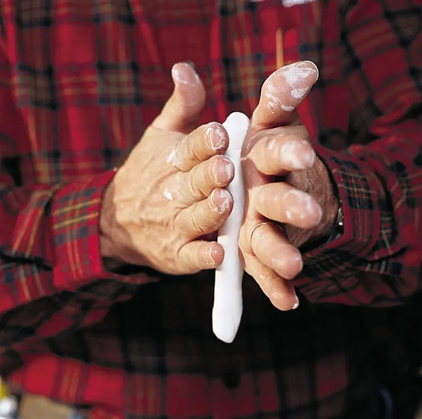 A person kneading putty for a window pane in their hands.