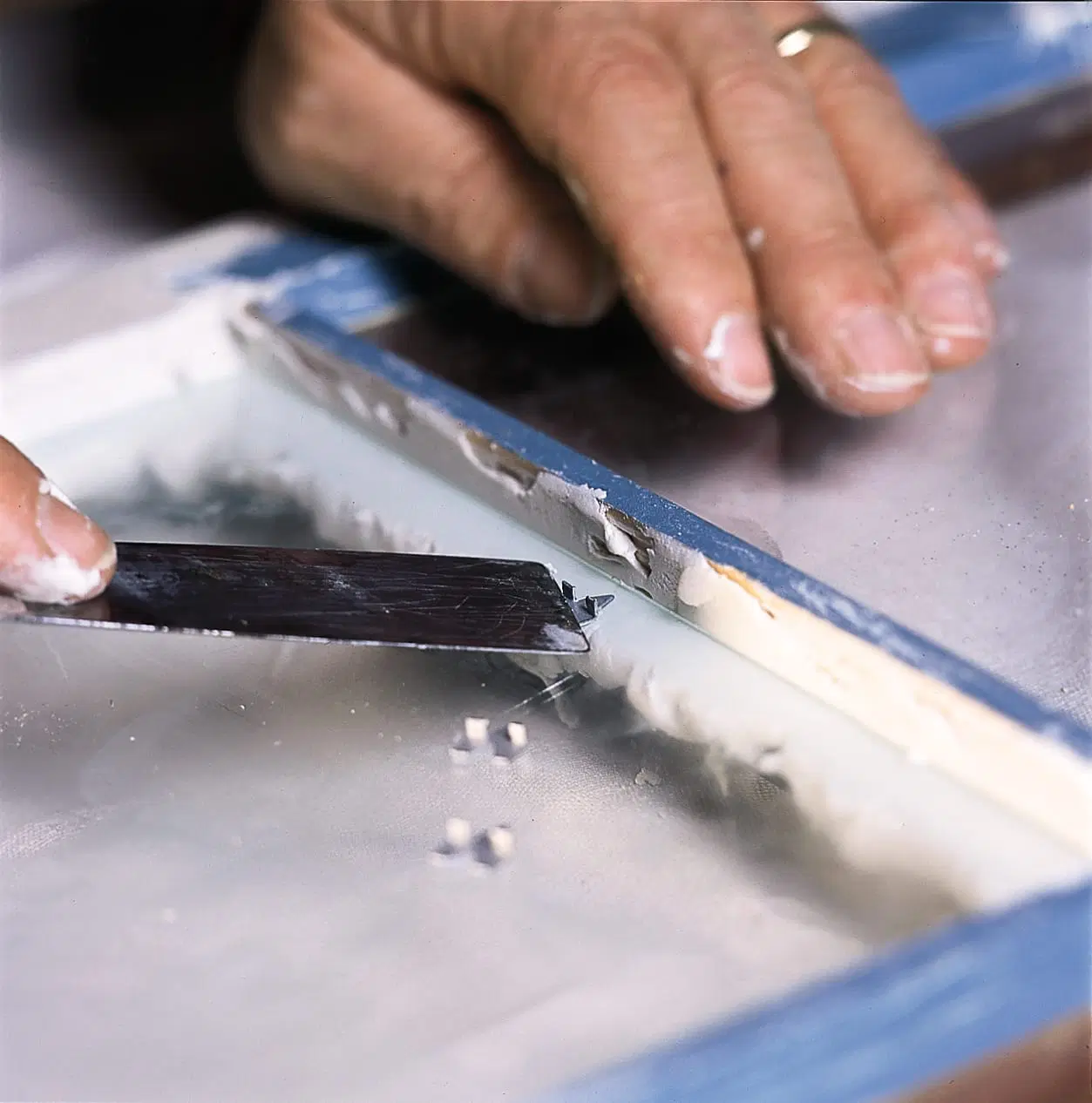 A glazier's point being use to set the points of a window pane.