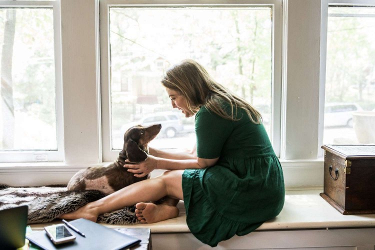 woman with dachshund sitting on window seat