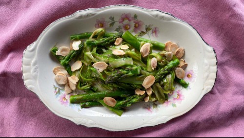 Sautéed asparagus on a plate with sliced almonds