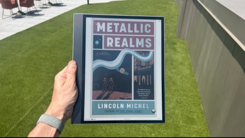 An ebook cover displayed in color on the Tab X C, with the device being held in one hand in an outdoor setting