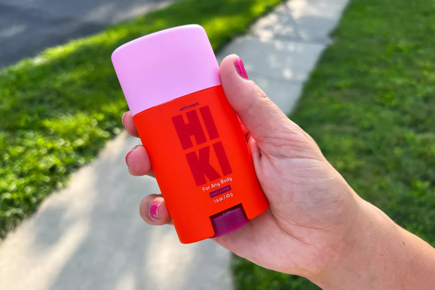 A person holds up the Hiki Anti-Chafe Stick