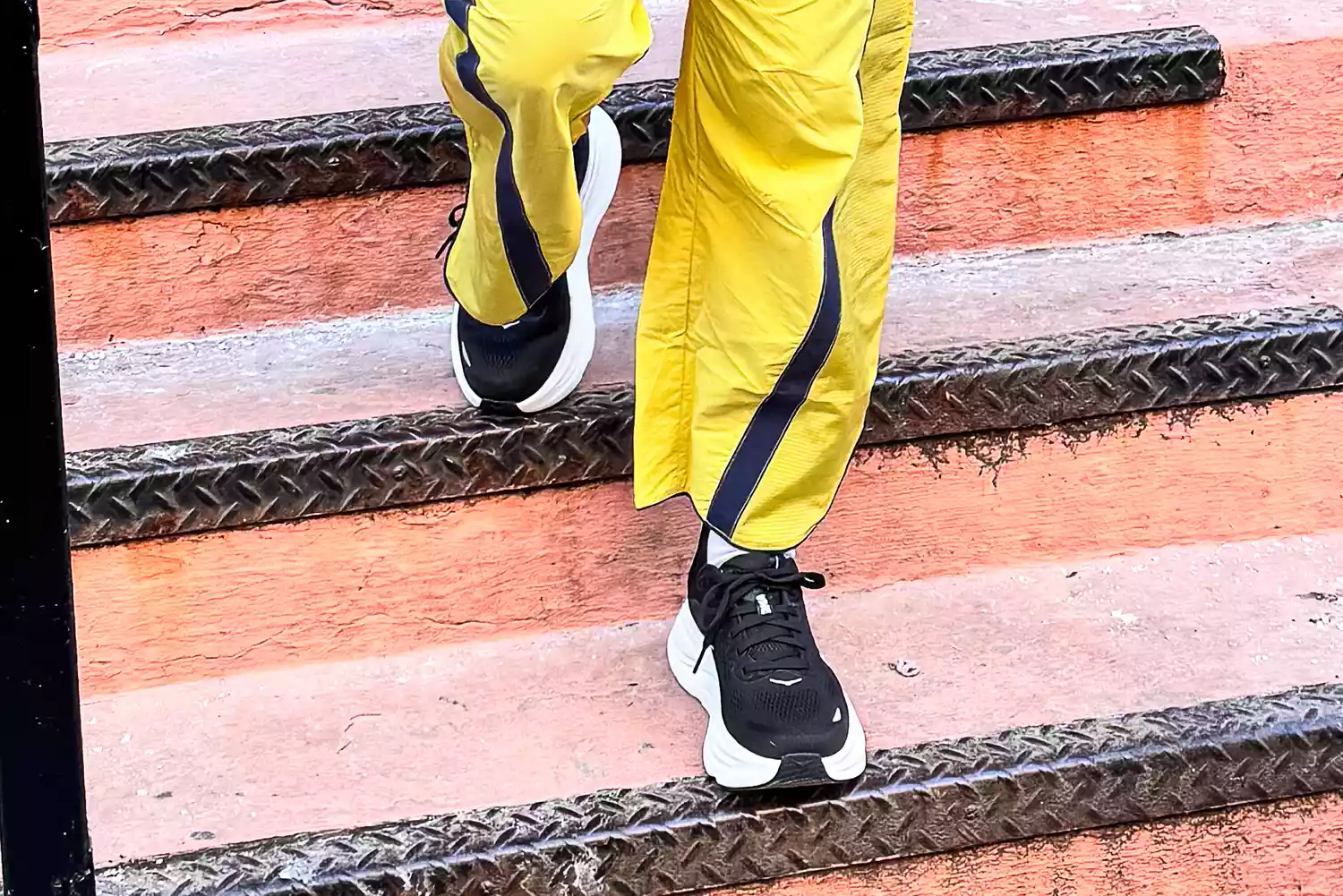 Close-up of a woman's legs and feet wearing Hoka Bondi 9 sneakers and Free People's Champ Is Here Pants