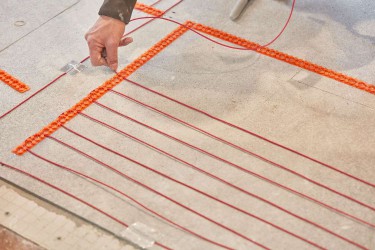 Radiant heat flooring system orange wires being installed on ground