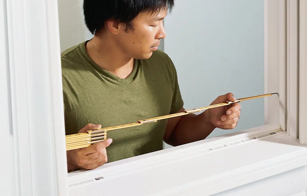 A man taking measurements for interior shutters.