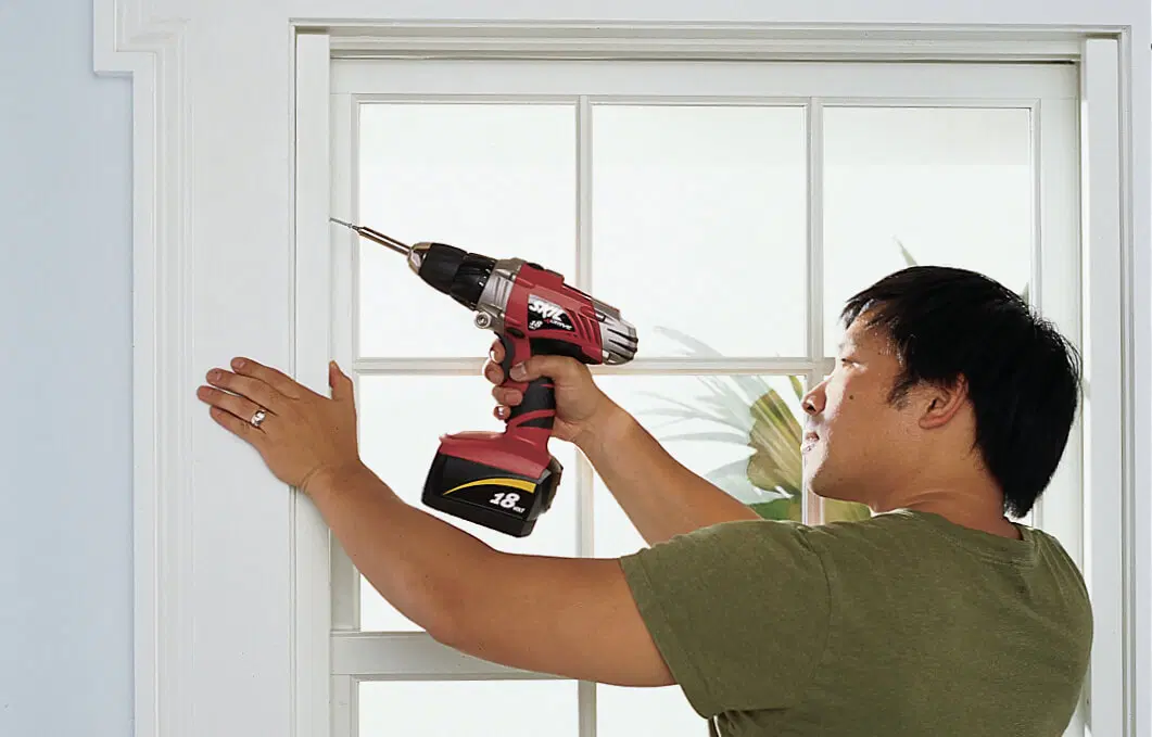 A drill being used to install a window shutter.