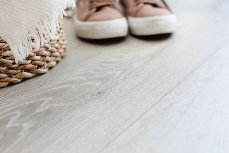 Laminate flooring of light stained wood with basket and shoes on top closeup