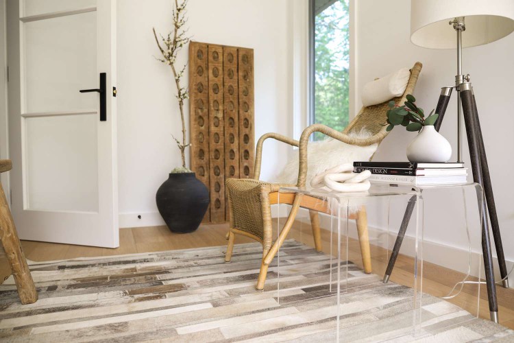 Wooden chair and glass side table moved out of the walk way with neutral-colored rug in middle