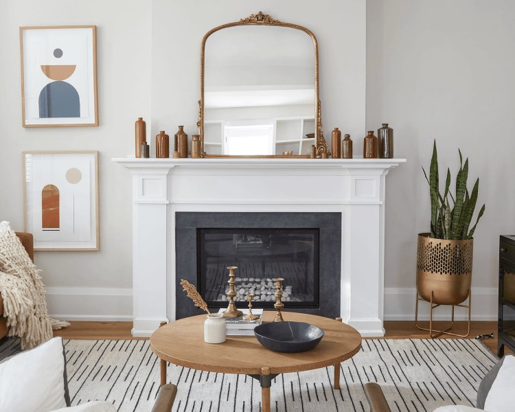 A white fireplace mantel lined with brown vases and a large gold ornate mirror