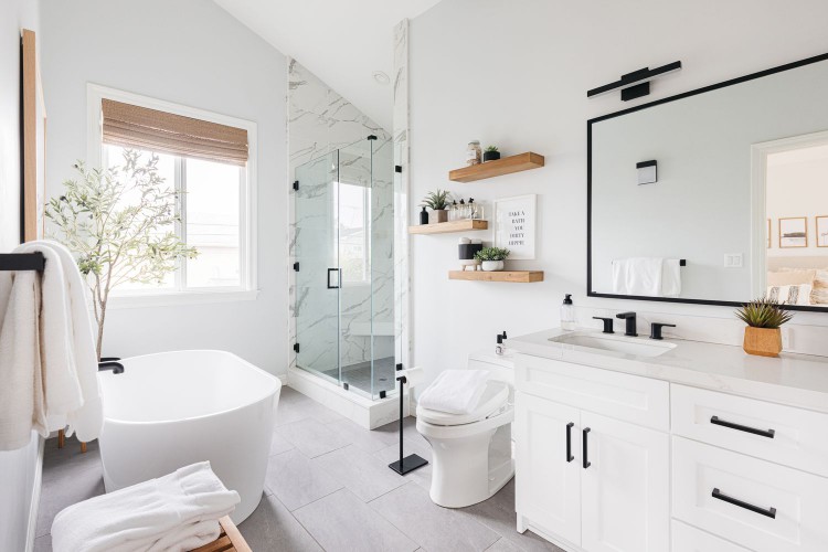 Large and bright primary bathroom with white fixtures and glass shower doors