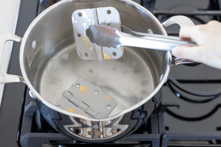 using tongs to submerge the painted items