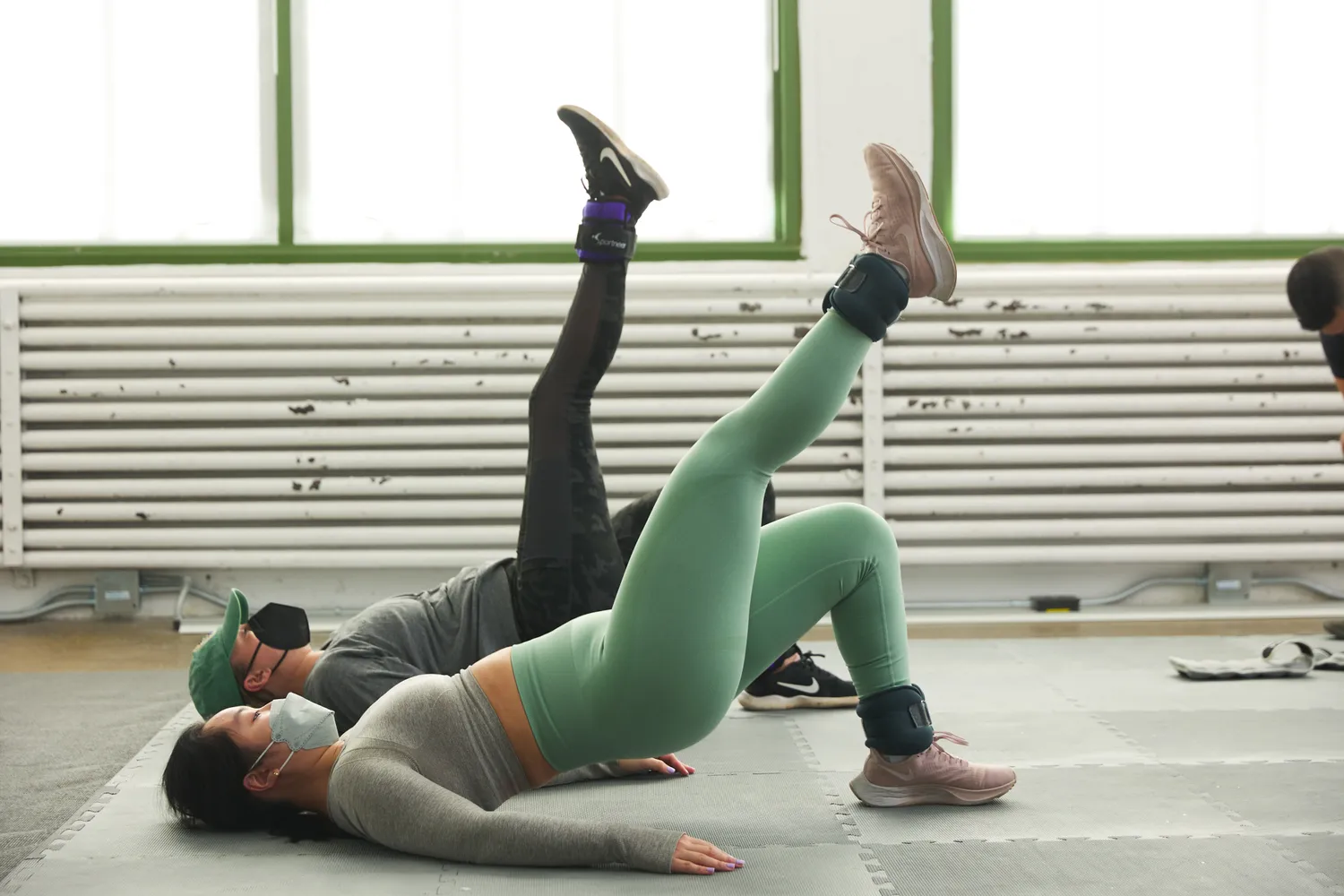 person doing floor exercises with others while wearing the P Volve 3 LB Ankle Weights