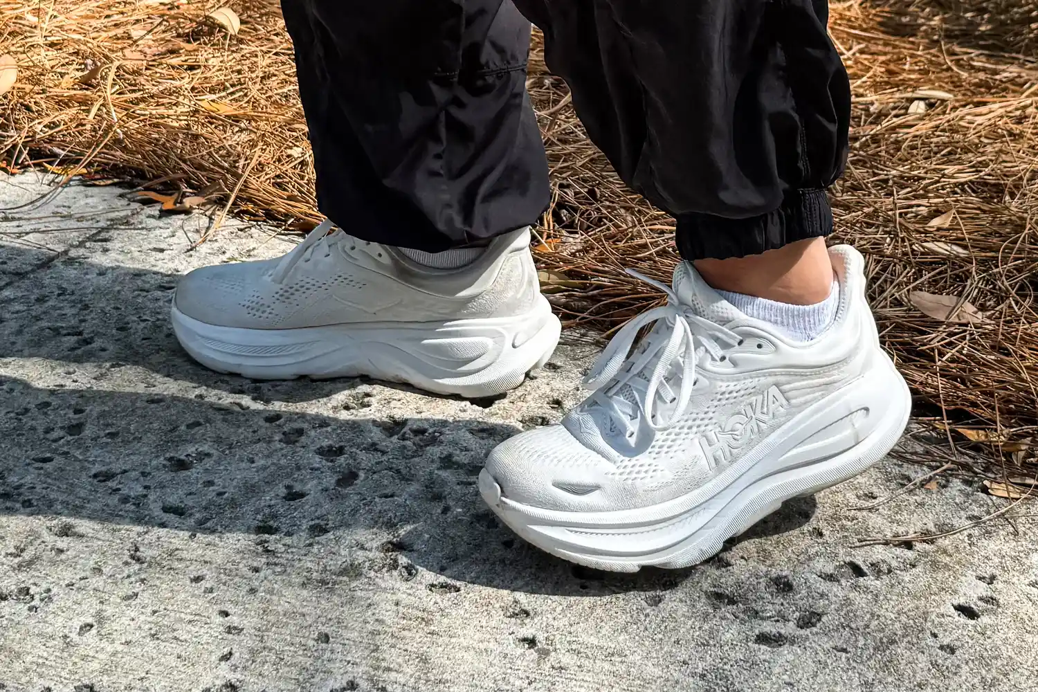 A person walks outside while wearing the HOKA Men's Bondi 9 Running Shoes