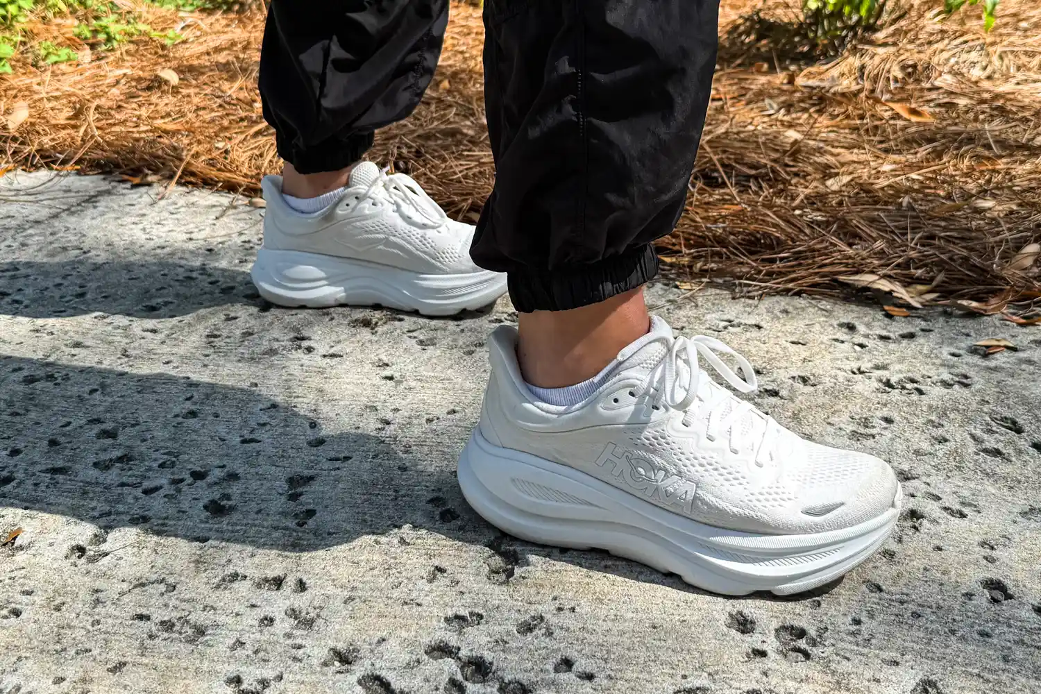 A person wears the HOKA Men's Bondi 9 Running Shoes while walking outside