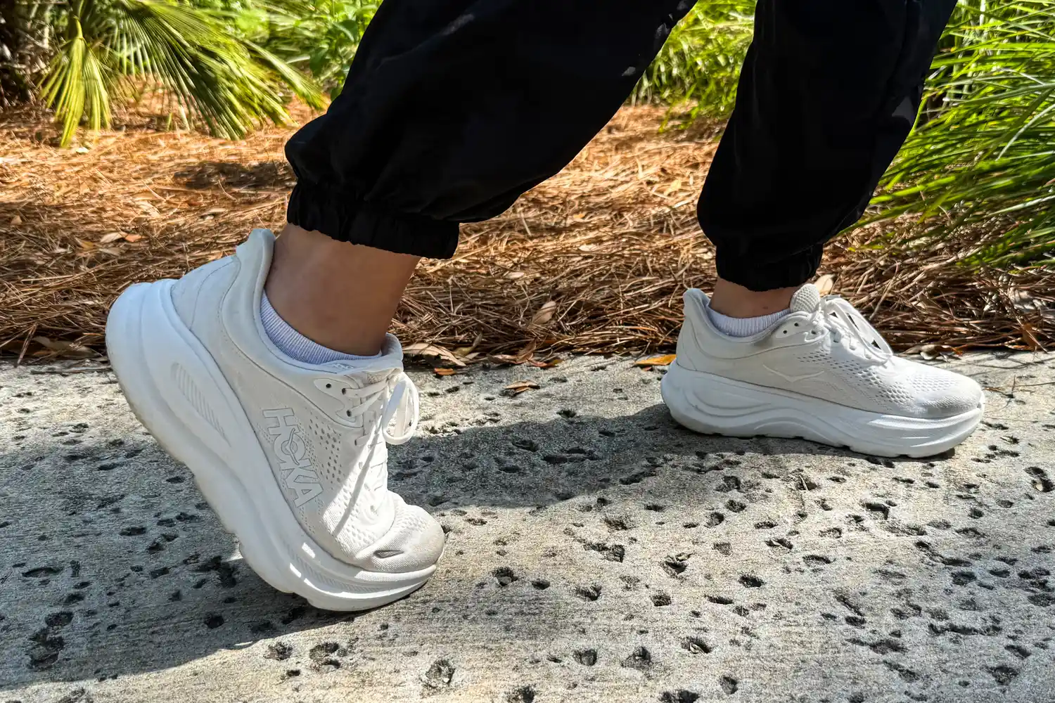A person walks outside while wearing the HOKA Men's Bondi 9 Running Shoes