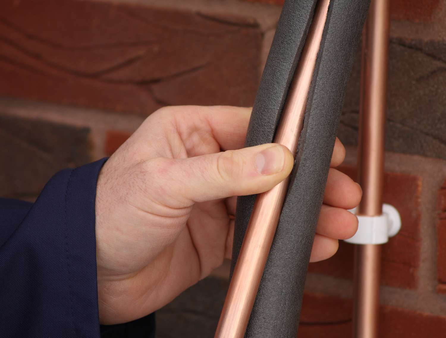 Plumber insulating a copper water pipe