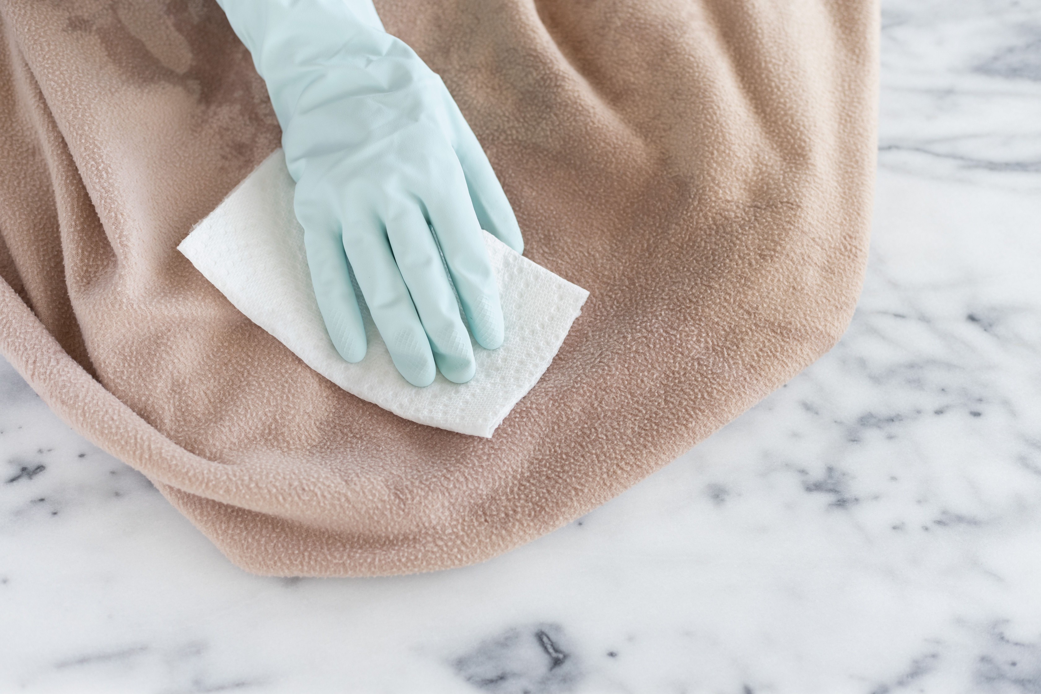 Bedding with cat urine wiped with soaked paper towel and light blue gloves