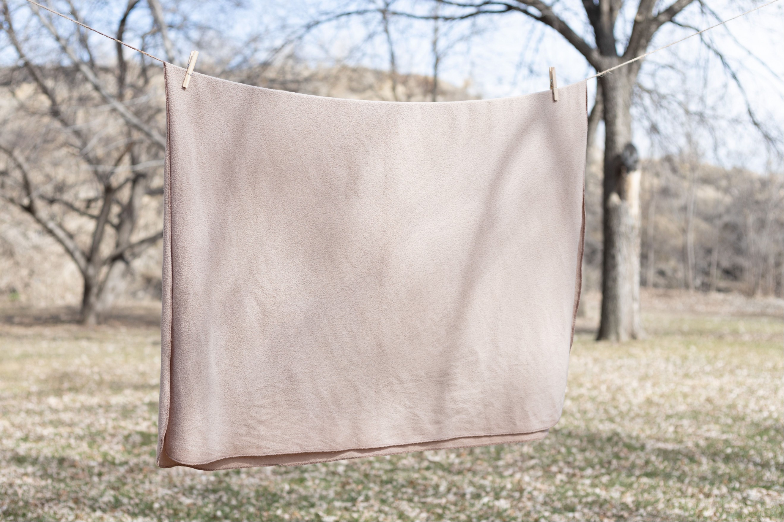 Tan bedding hanging on line wire outside to air dry