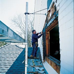 A man constructing a second story bay window.