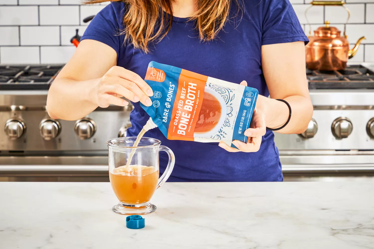 A person pours Bare Bones Grass-Fed Beef Organic Bone Broth into a glass