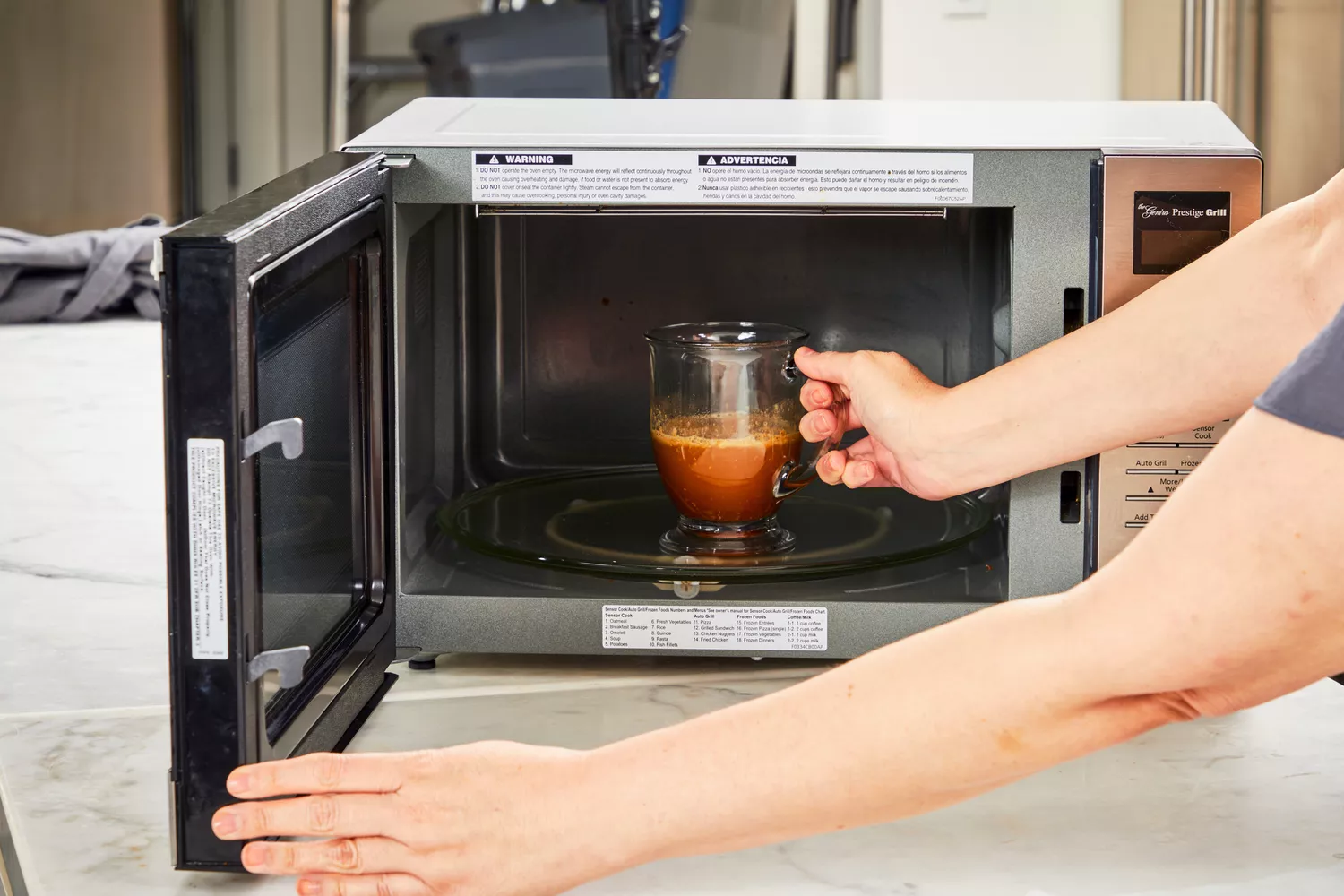 A person puts a glass of Bare Bones Bone Broth Instant Powdered Beverage Mix into a microwave
