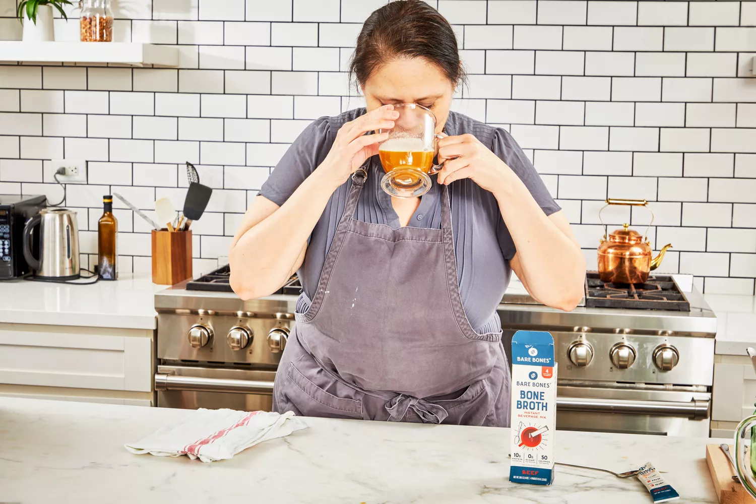 A person drinks a glass of Bare Bones Bone Broth Instant Powdered Beverage Mix