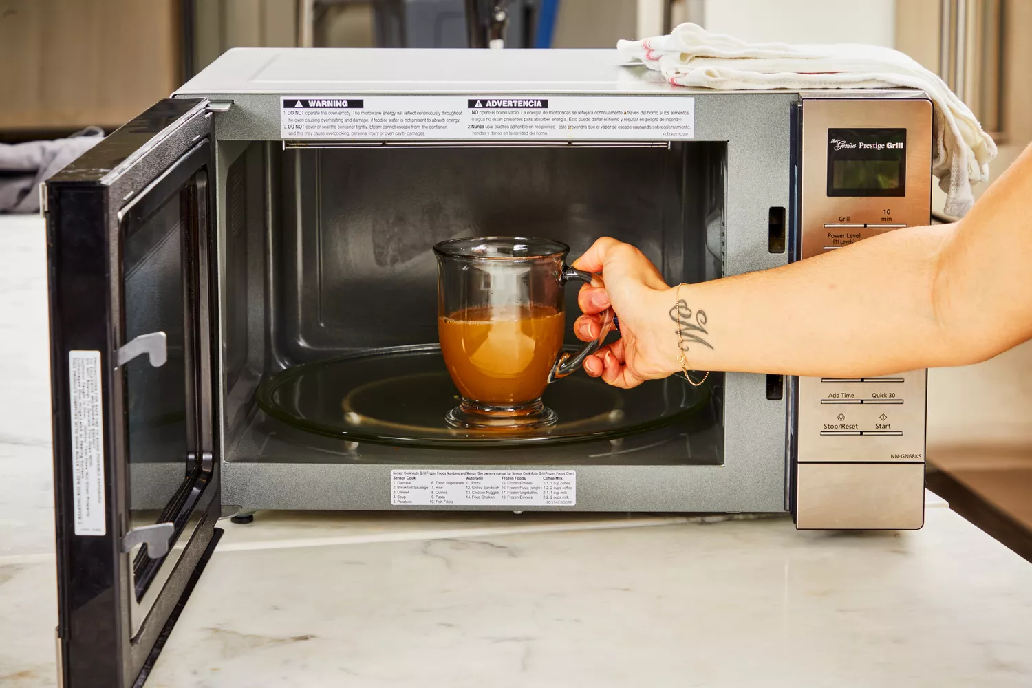 A person places a glass of Swanson Sipping Chicken Bone Broth into a microwave