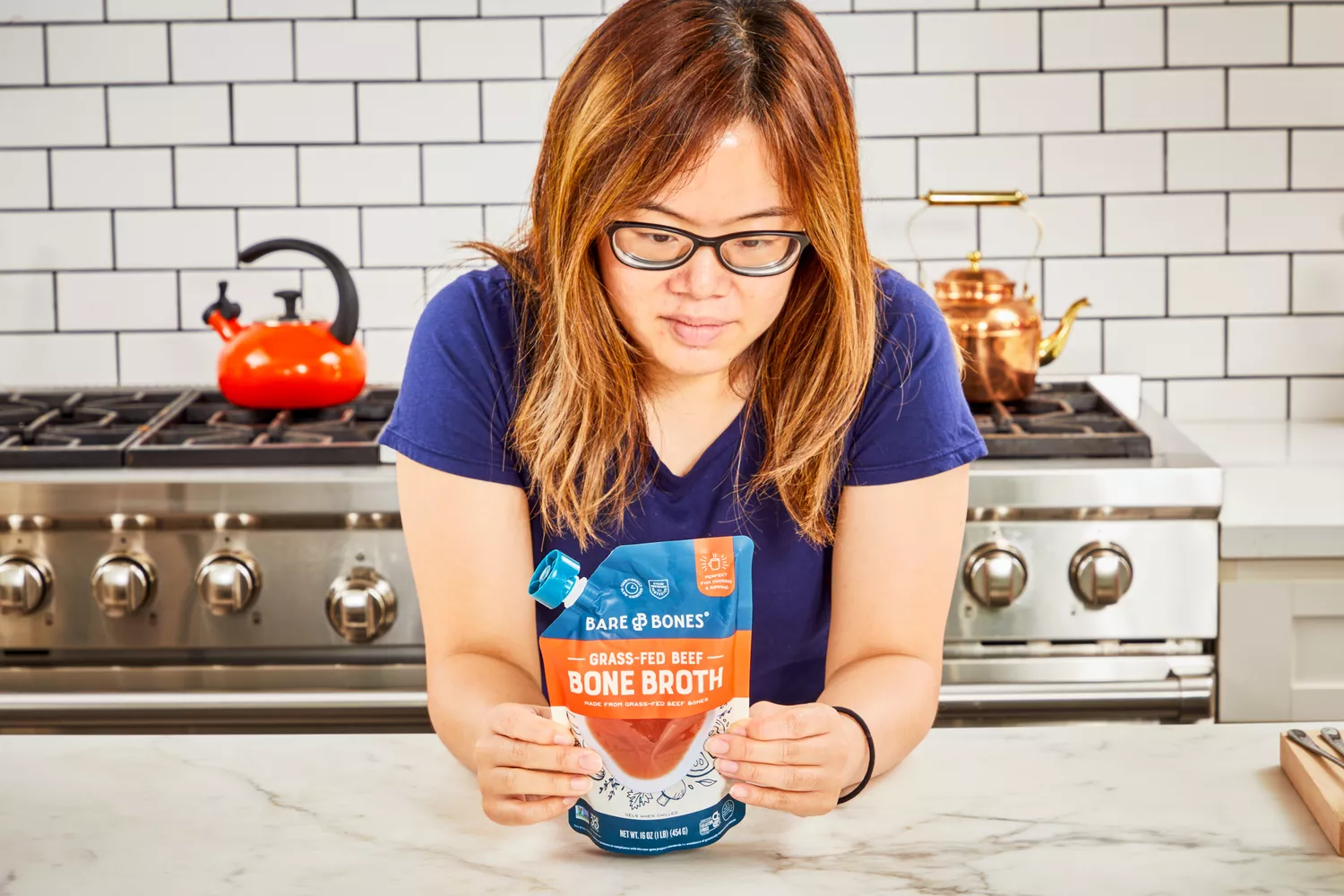 A person reads a package of Bare Bones Grass-Fed Beef Organic Bone Broth