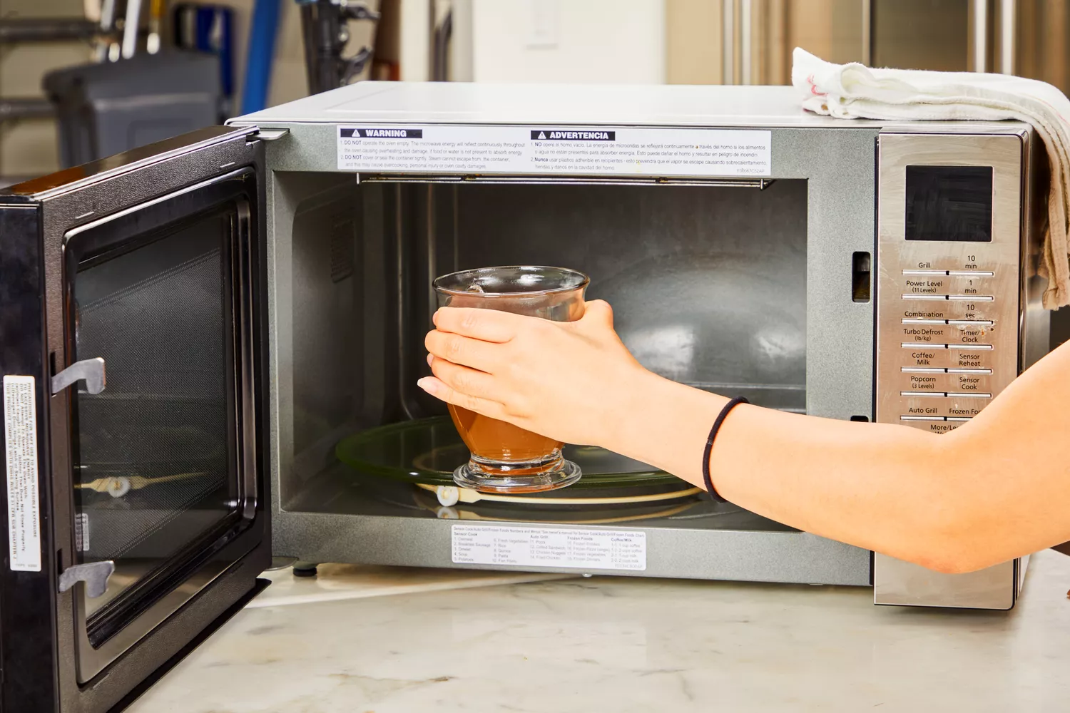 A person microwaves a glass of Bare Bones Grass-Fed Beef Organic Bone Broth