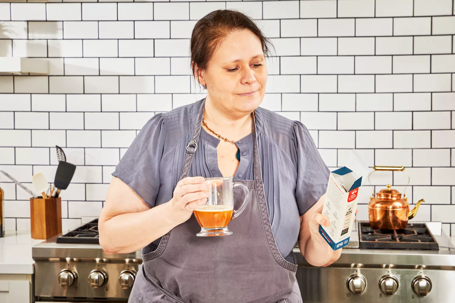 A person holds a glass of Bare Bones Bone Broth Instant Powdered Beverage Mix