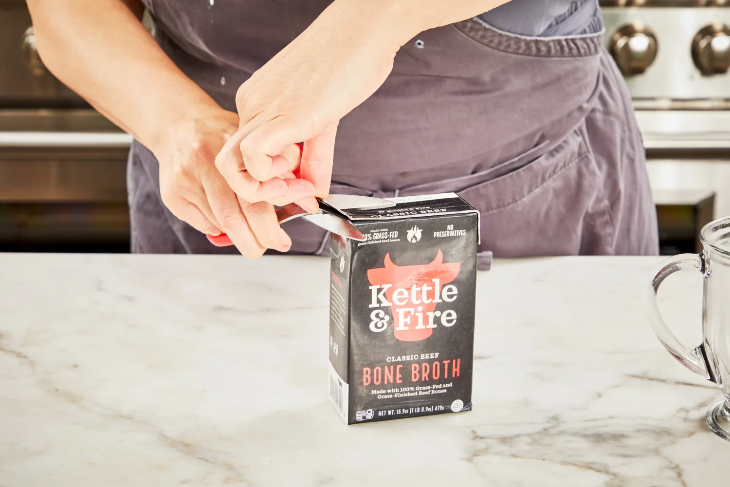 A person opens a box of Kettle &amp; Fire Bone Broth