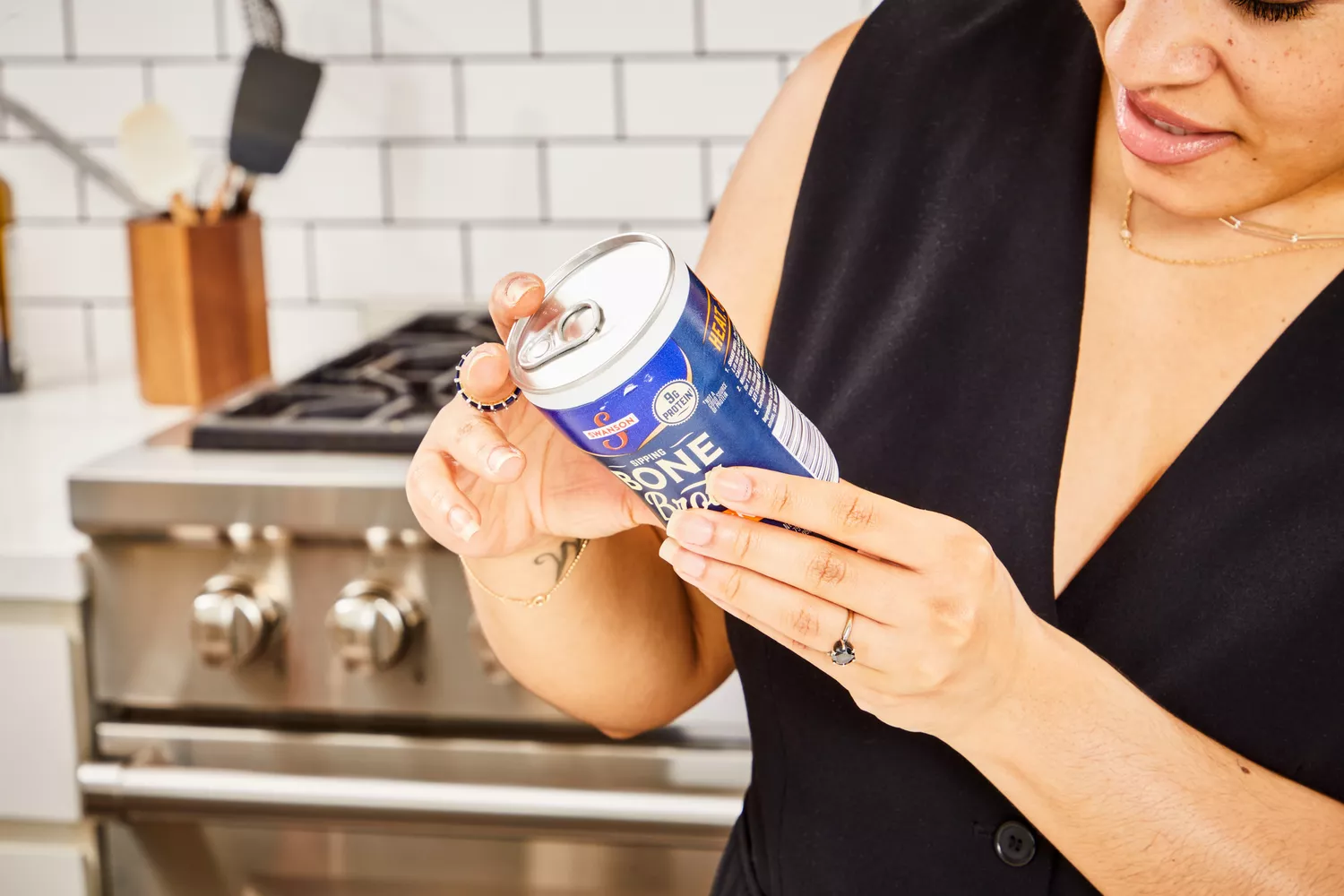 A person reads a canister of Swanson Sipping Chicken Bone Broth