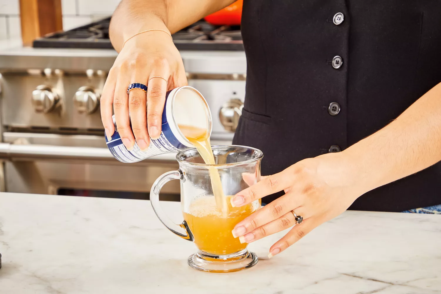 A person pours Swanson Sipping Chicken Bone Broth into a glass