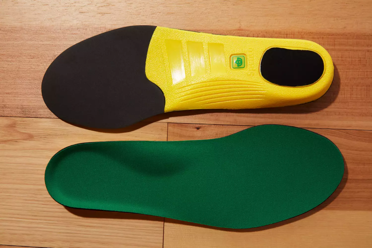 Spenco PolySorb Cross Trainer Insoles showing the top and bottom displayed on a wood floor
