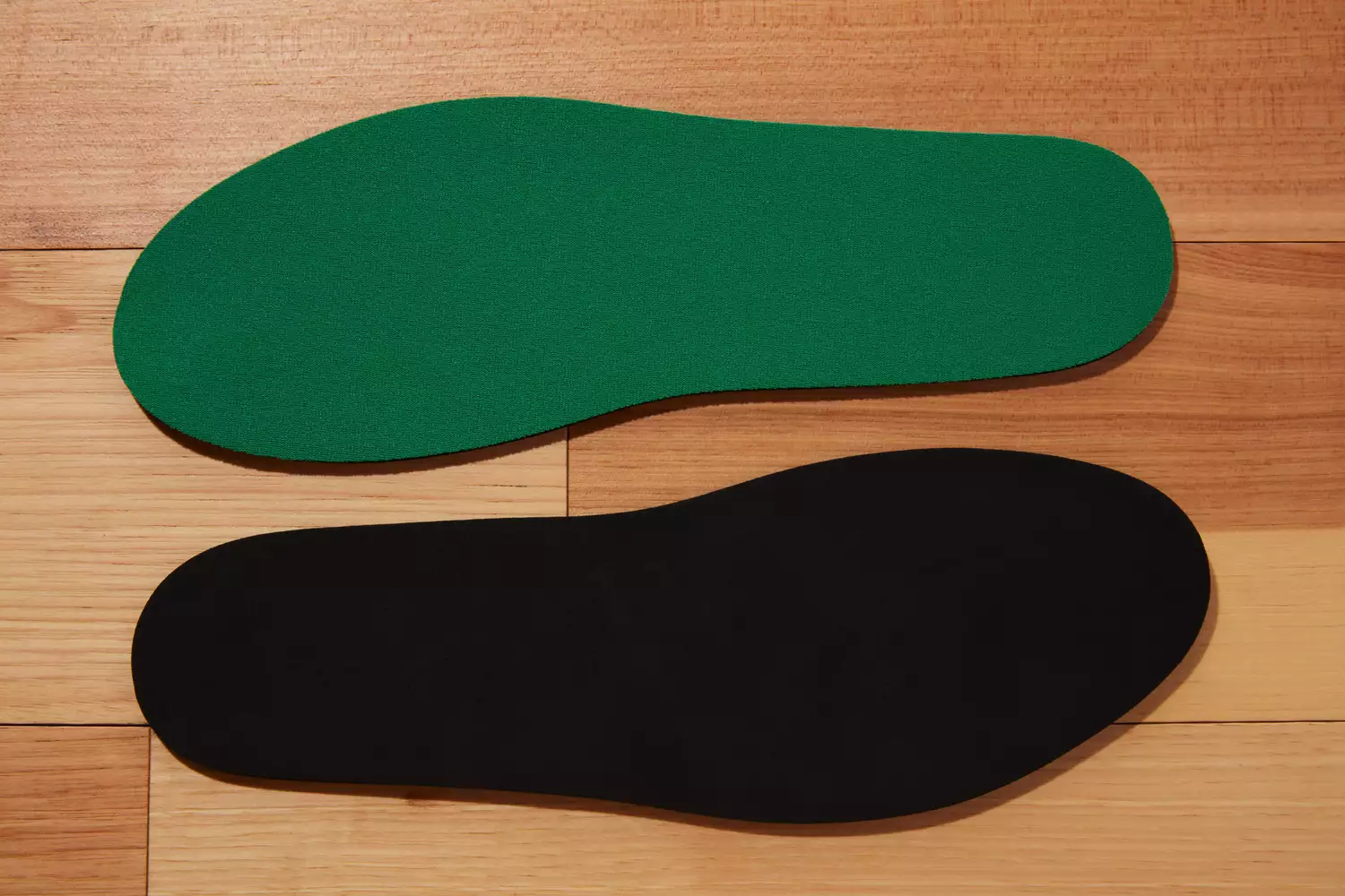 Both sides of Spenco RX Comfort Insoles displayed on a wood surface