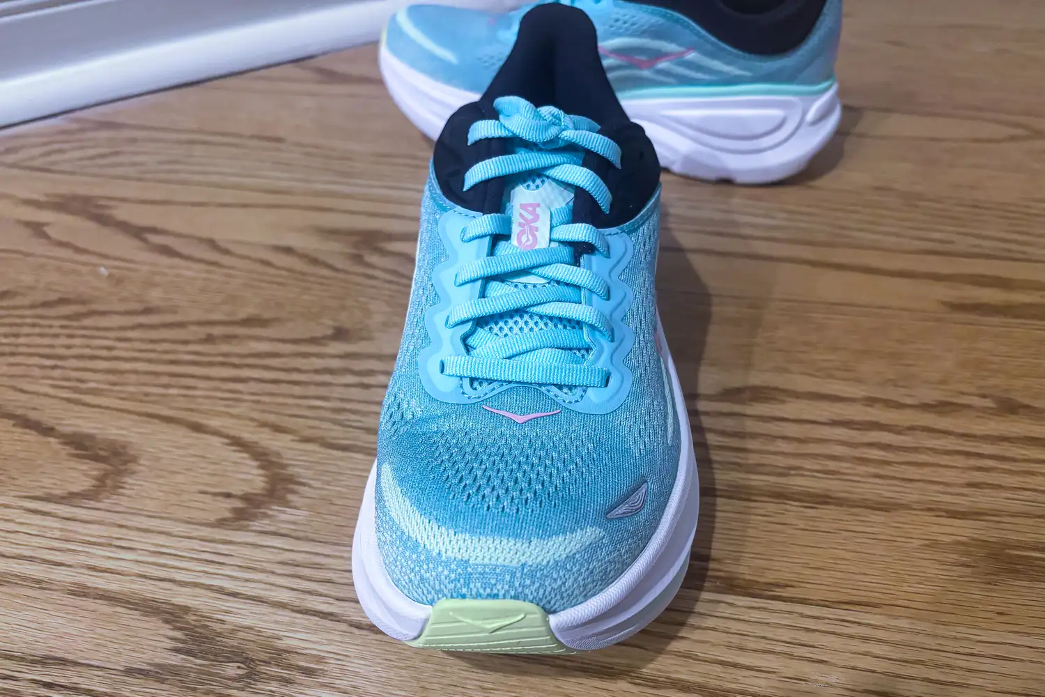 A pair of running shoes on a wooden floor focused on the front shoe