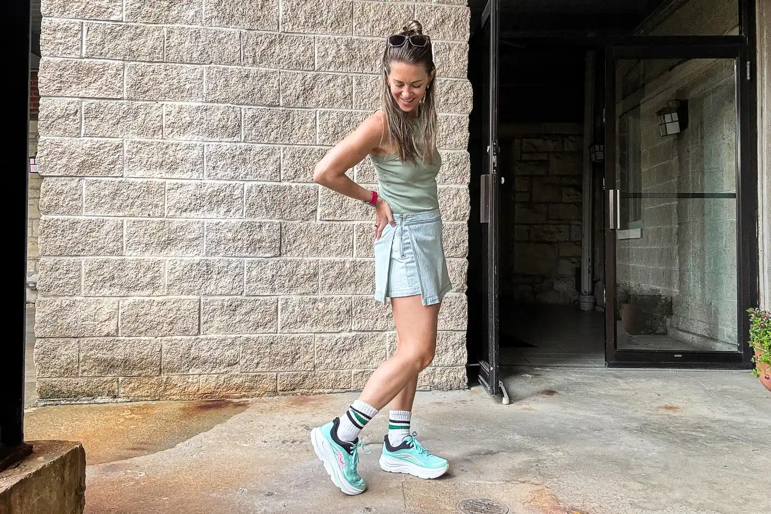 A person standing outdoors leaning slightly and wearing athletic footwear