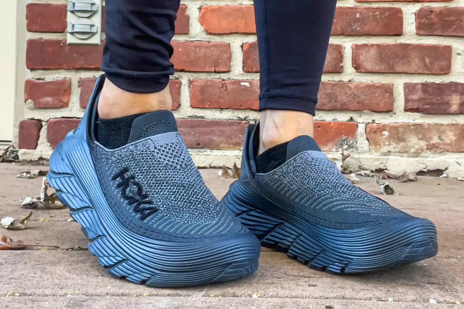 A person walks outside while wearing the Hoka Restore TC Recovery Shoes