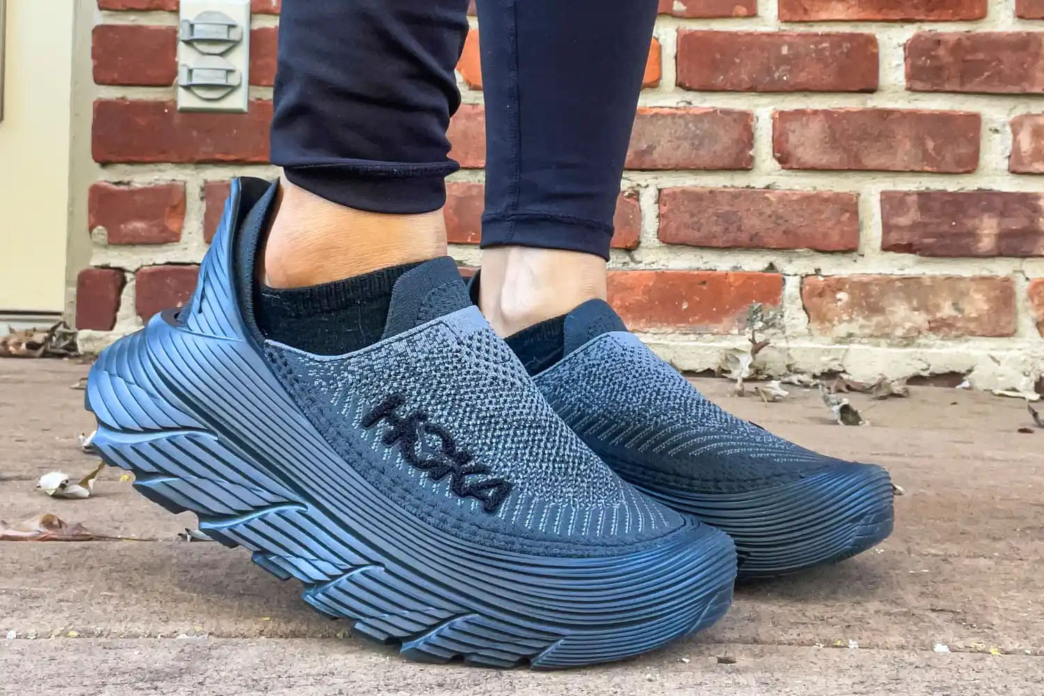 A person walks outside while wearing the Hoka Restore TC Recovery Shoes