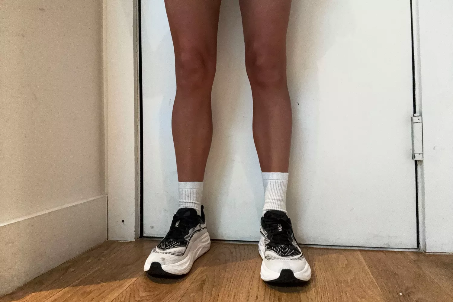 A person stands inside while wearing the HOKA Women's Skyflow Running Shoes