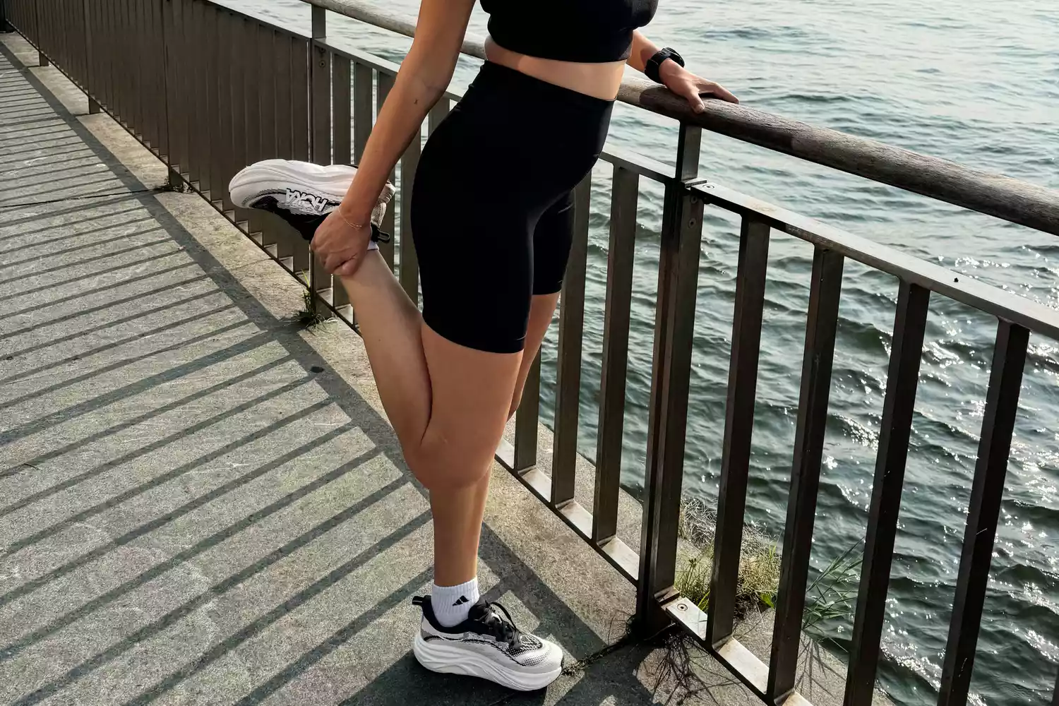 A person stretches while wearing the HOKA Women's Skyflow Running Shoes