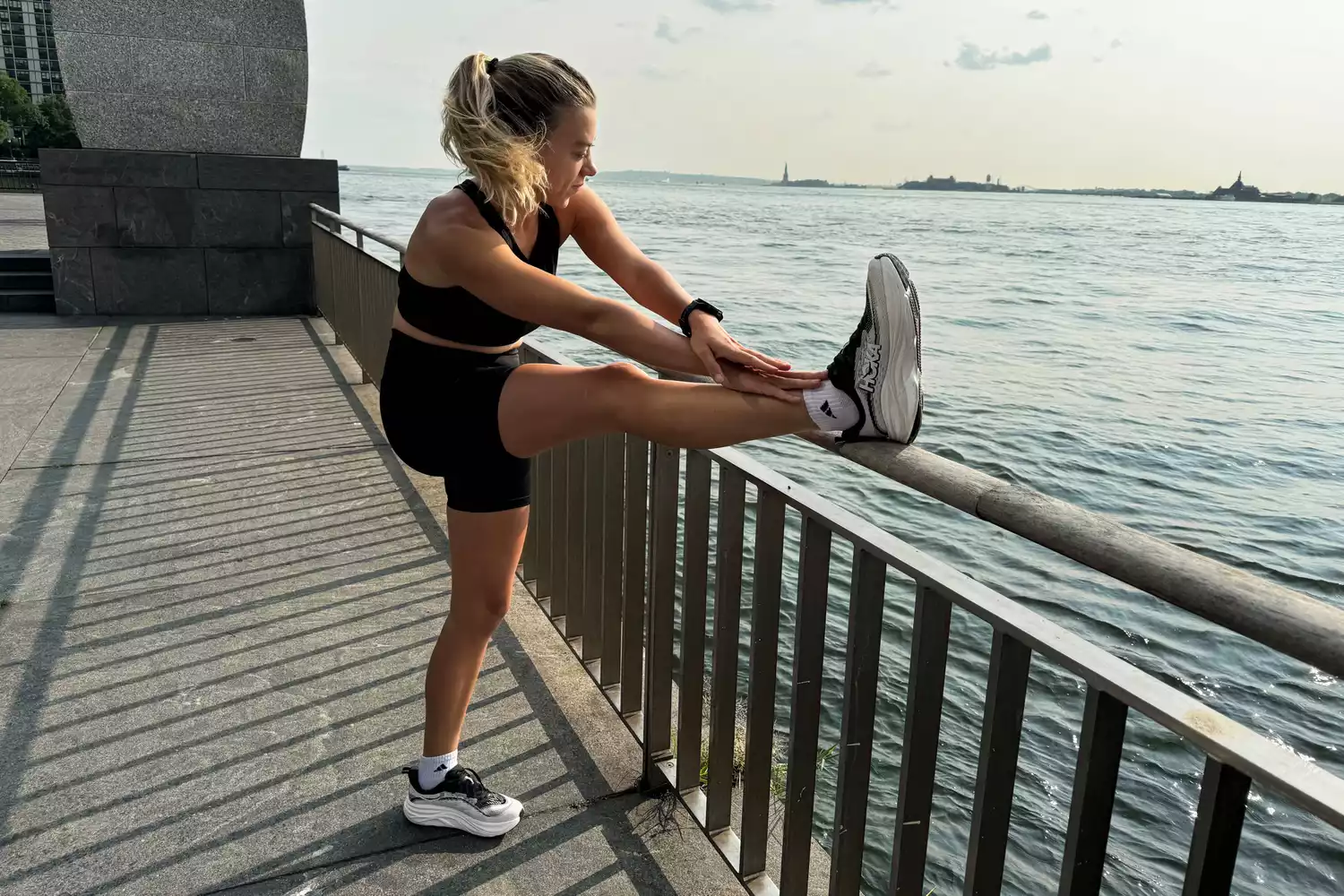A person stretches while wearing the HOKA Women's Skyflow Running Shoes