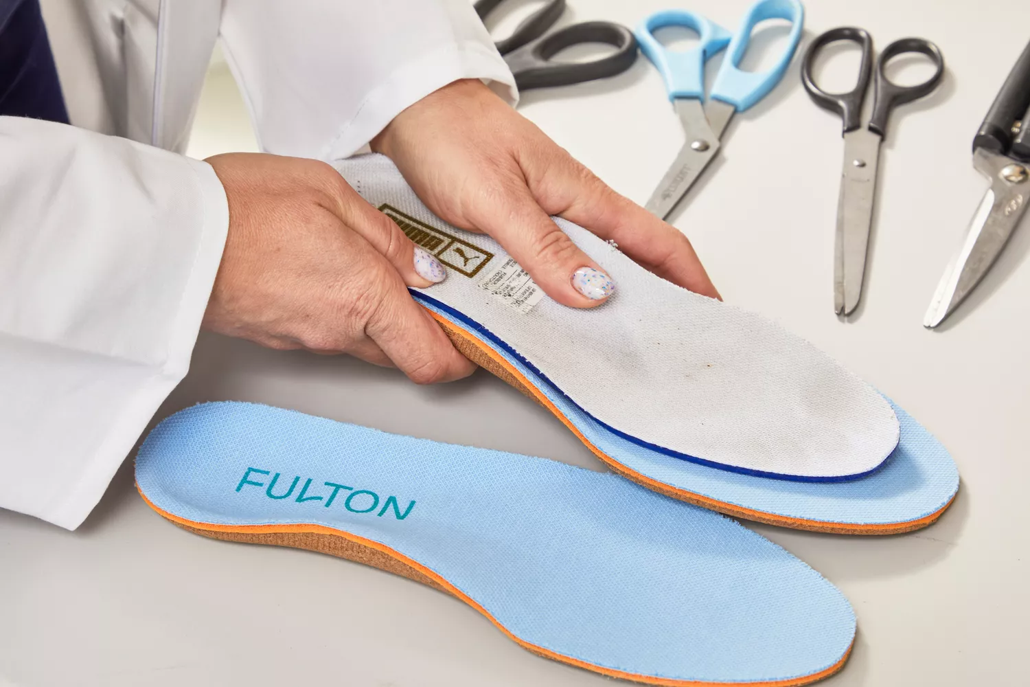 Hands holding a shoe insole on top of a Fulton Athletic Insole