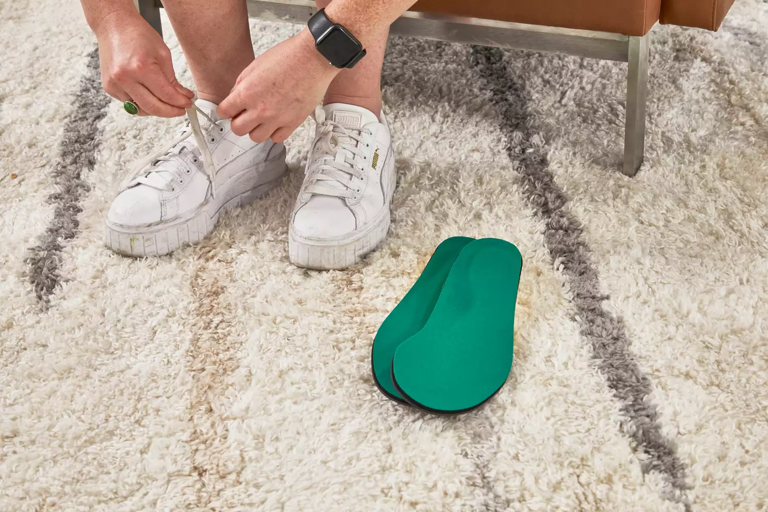 Hands untying sneaker next to Spenco PolySorb Cross Trainer Insoles