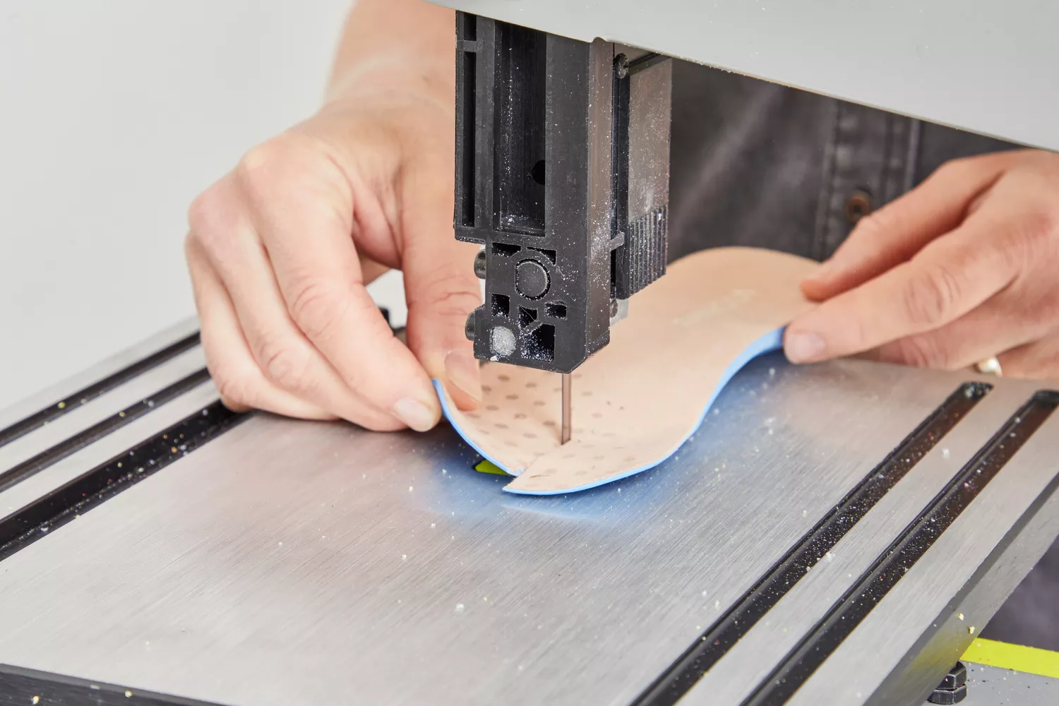 A person cutting the Vionic Slimfit Orthotic Insoles on a band saw